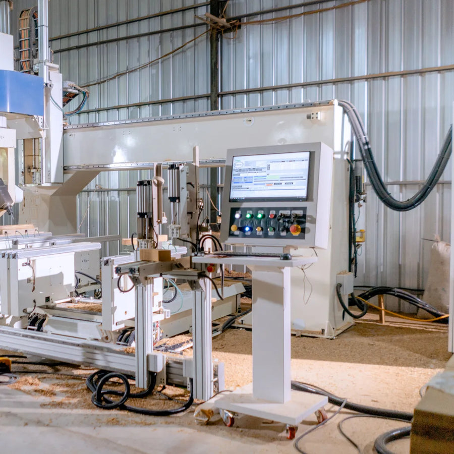 Operator station with a control screen beside an automated CNC machine on a manufacturing floor.