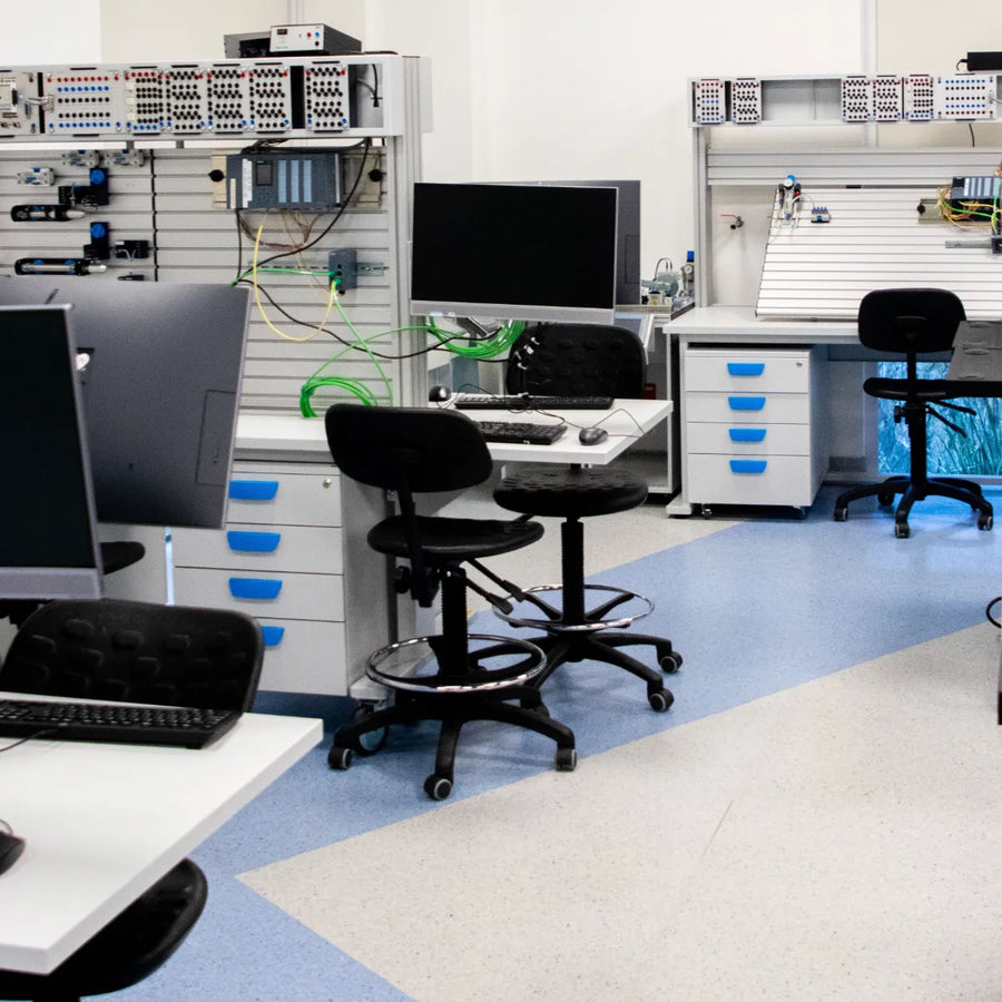 Engineering test bench with a computer workstation and a panel of wired control hardware in a test lab.